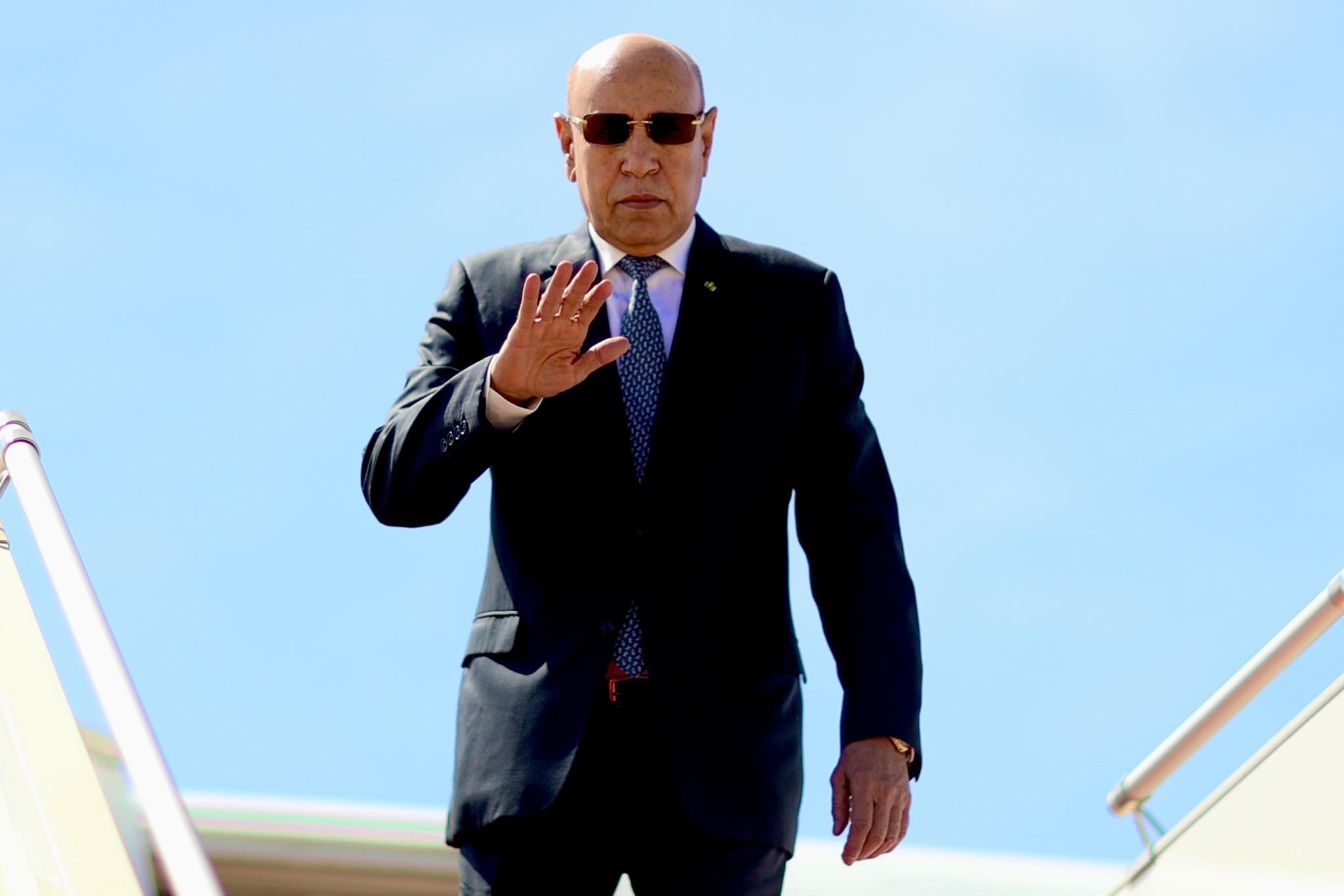 Le président mauritanien salue de la main sur la passerelle d'un avion