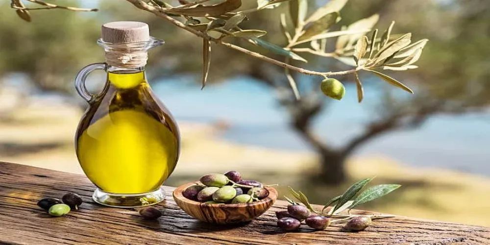 Une bouteille en verre d'huile d'olive et un bol d'olives sur une table en bois, photo d'archives