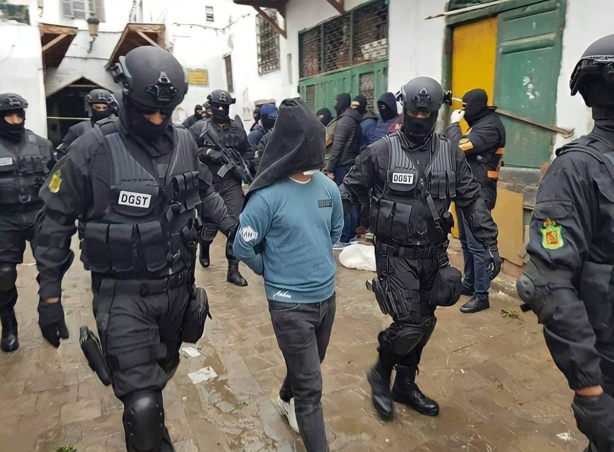 Des agents de la DGST escortent un suspect à la tête couverte lors d'une précédente opération