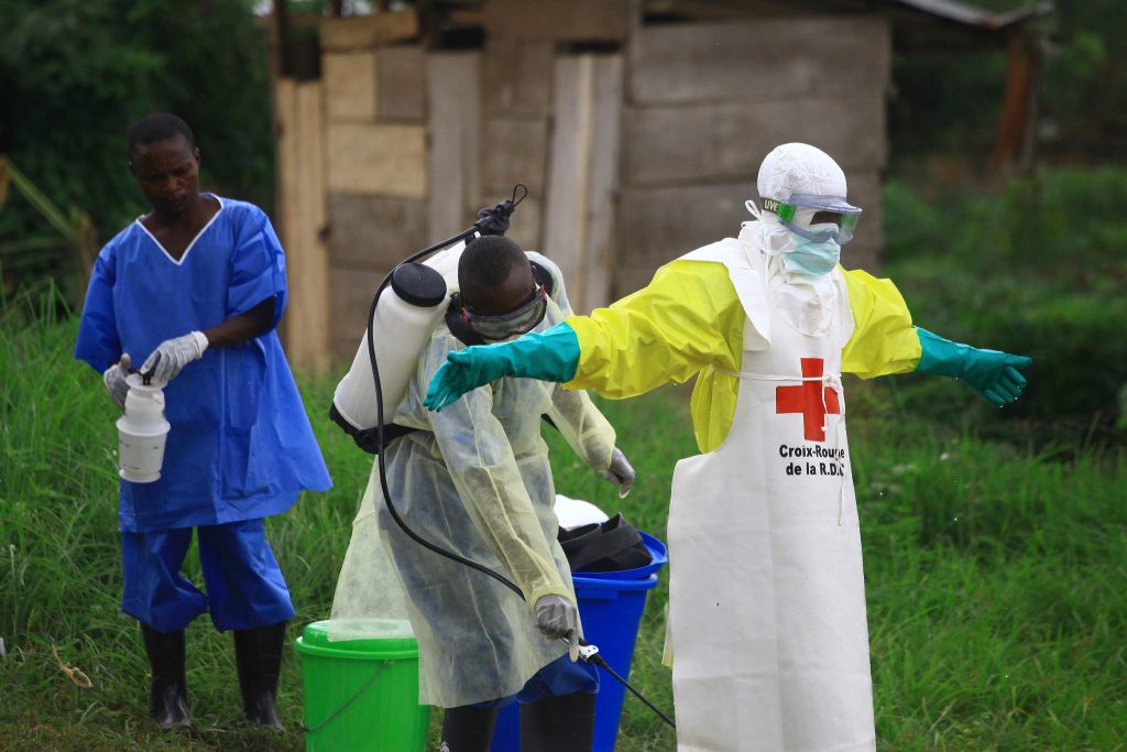 Agent de santé en combinaison de protection blanche et jaune de la Croix-Rouge congolaise désinfecté dans une zone herbeuse, photo d'archives