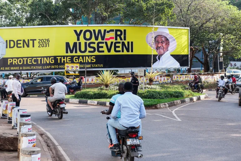 Des motos et des voitures dans une rue de Kampala près d'un grand panneau électoral, photo d'archives