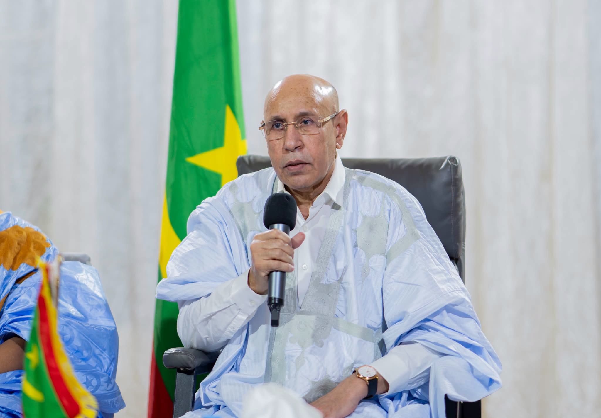 Le président mauritanien parle au micro lors d'une rencontre, devant le drapeau national