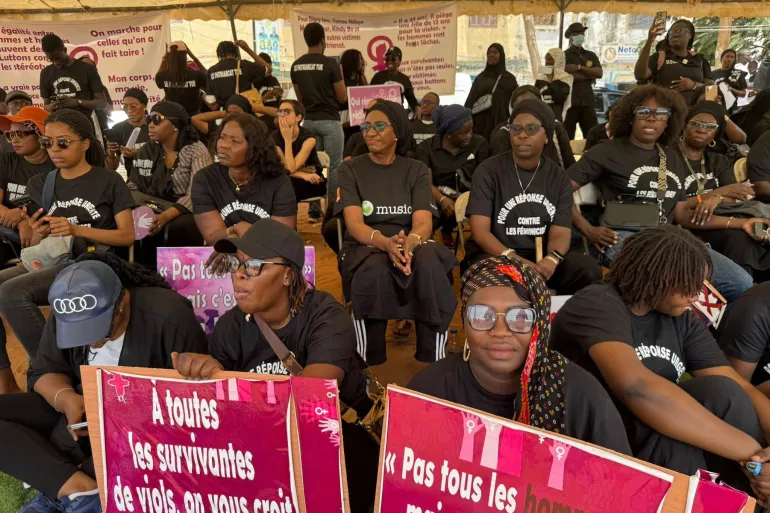Des femmes vêtues de noir brandissent des pancartes contre les violences faites aux femmes lors d'une manifestation à Dakar