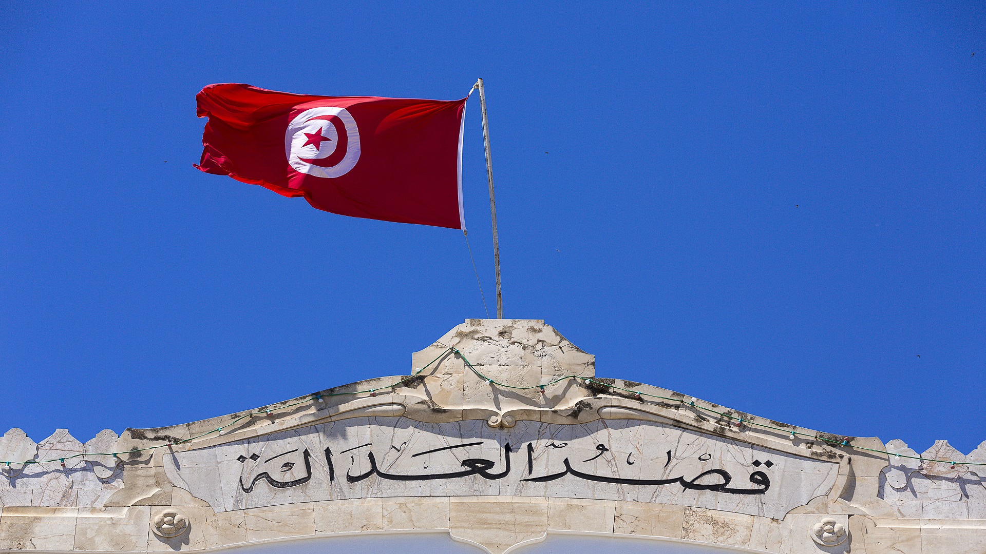 Le drapeau tunisien flotte au-dessus d'une façade en pierre portant l'inscription « Palais de justice » en arabe, photo d'archives