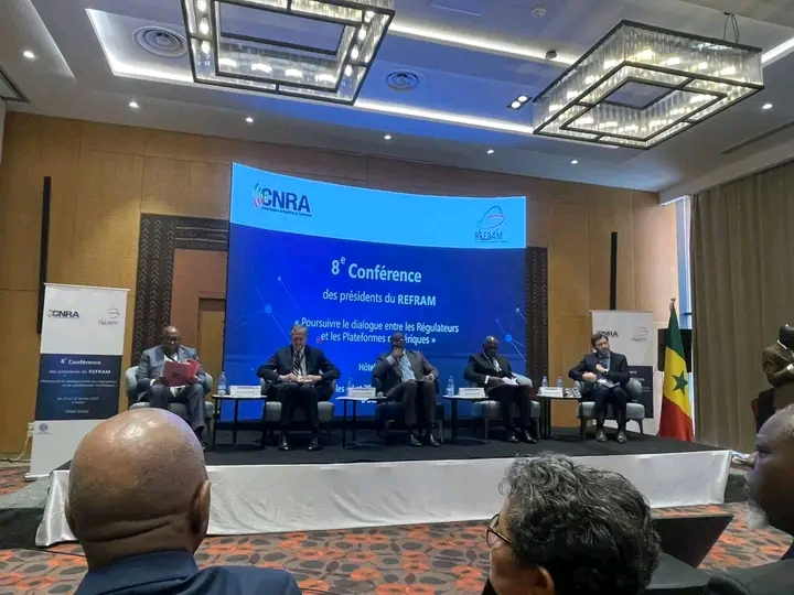 Cinq responsables assis sur la scène d'une conférence devant un écran annonçant la 8e conférence des présidents du REFRAM, photo d'archives