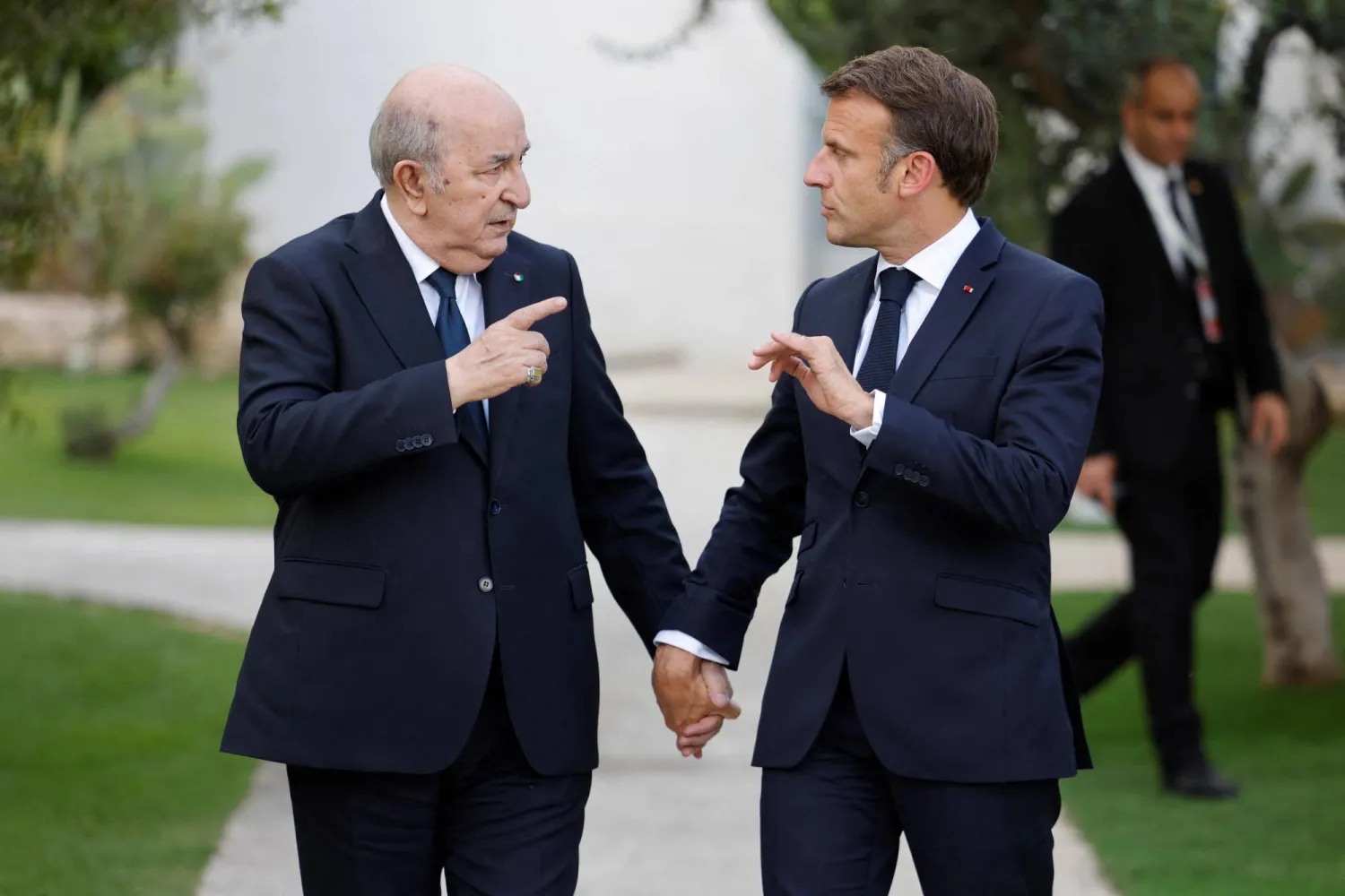 Abdelmadjid Tebboune et Emmanuel Macron marchant côte à côte dans un jardin