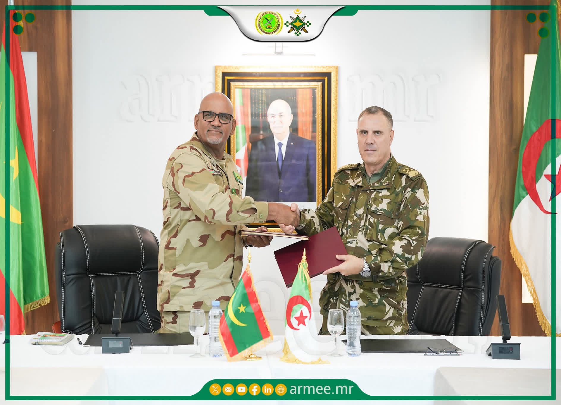 Deux officiers mauritanien et algérien échangent des documents, les drapeaux des deux pays sur la table