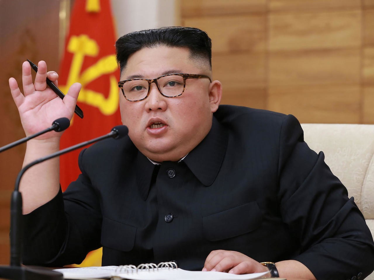 Le dirigeant nord-coréen Kim Jong Un parle derrière deux micros, un stylo à la main, photo d'archives