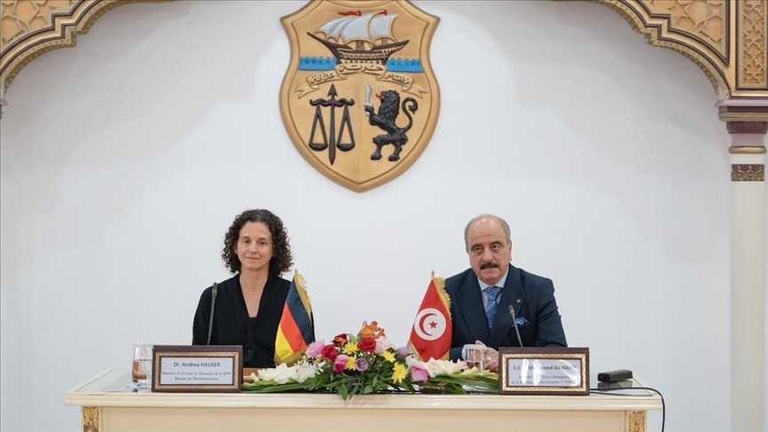 L'emblème de la République tunisienne accroché à un mur blanc derrière une table officielle portant les drapeaux tunisien et allemand, photo d'archives