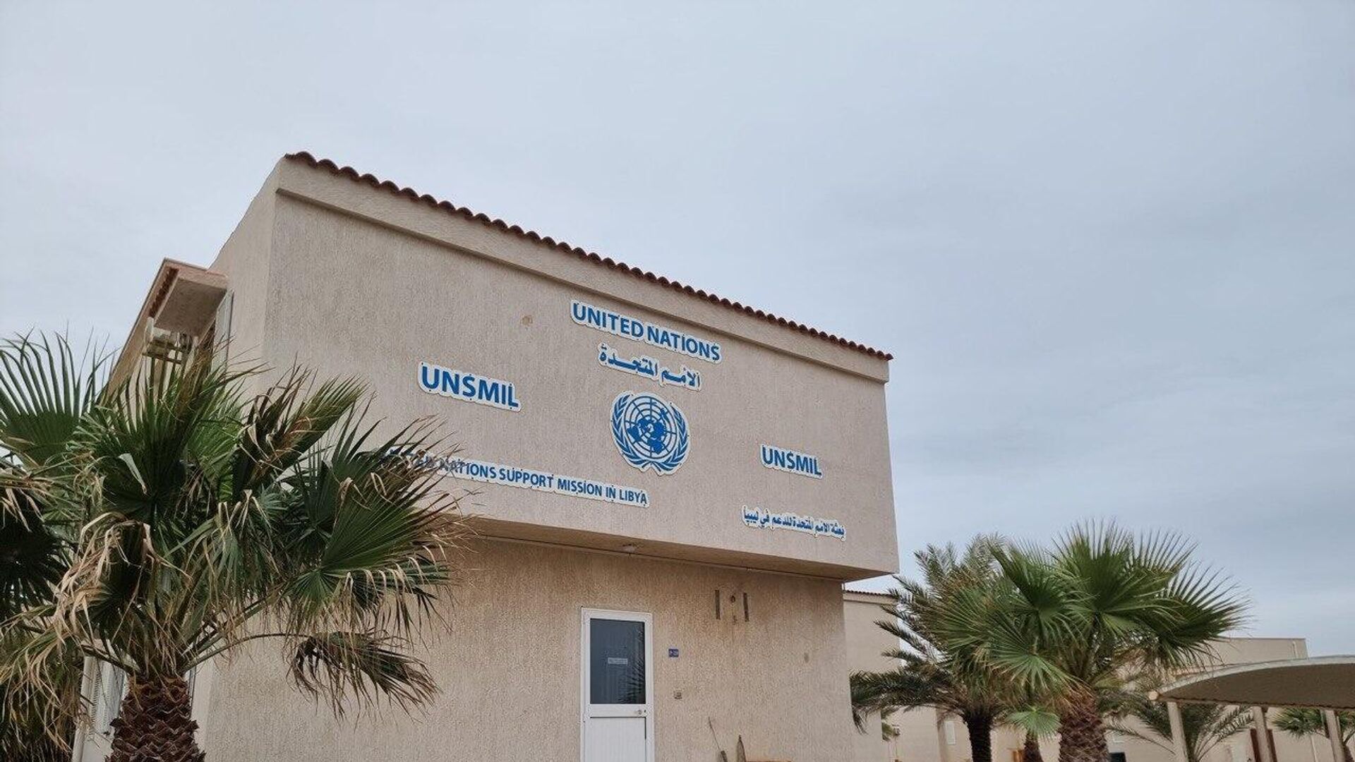 Bâtiment portant l'emblème des Nations unies et le nom de leur mission d'appui en Libye, entouré de palmiers, photo d'archives