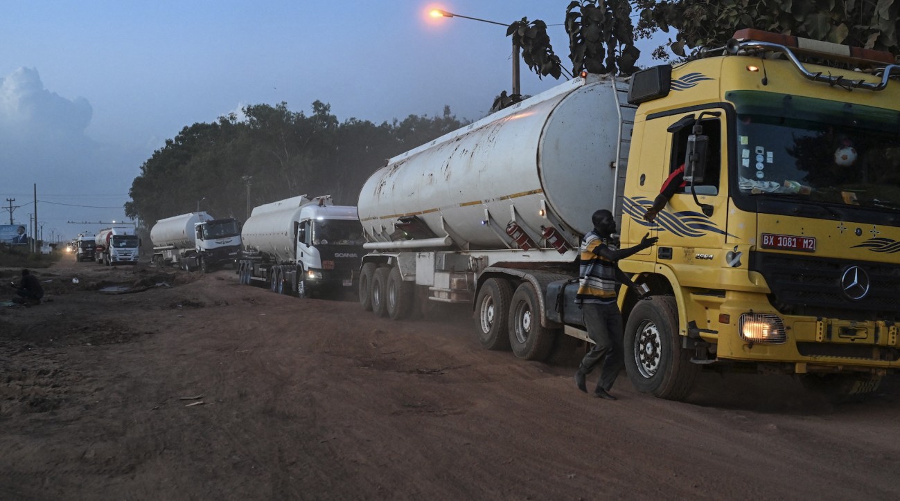 Une file de camions-citernes de carburant sur une route en terre au crépuscule