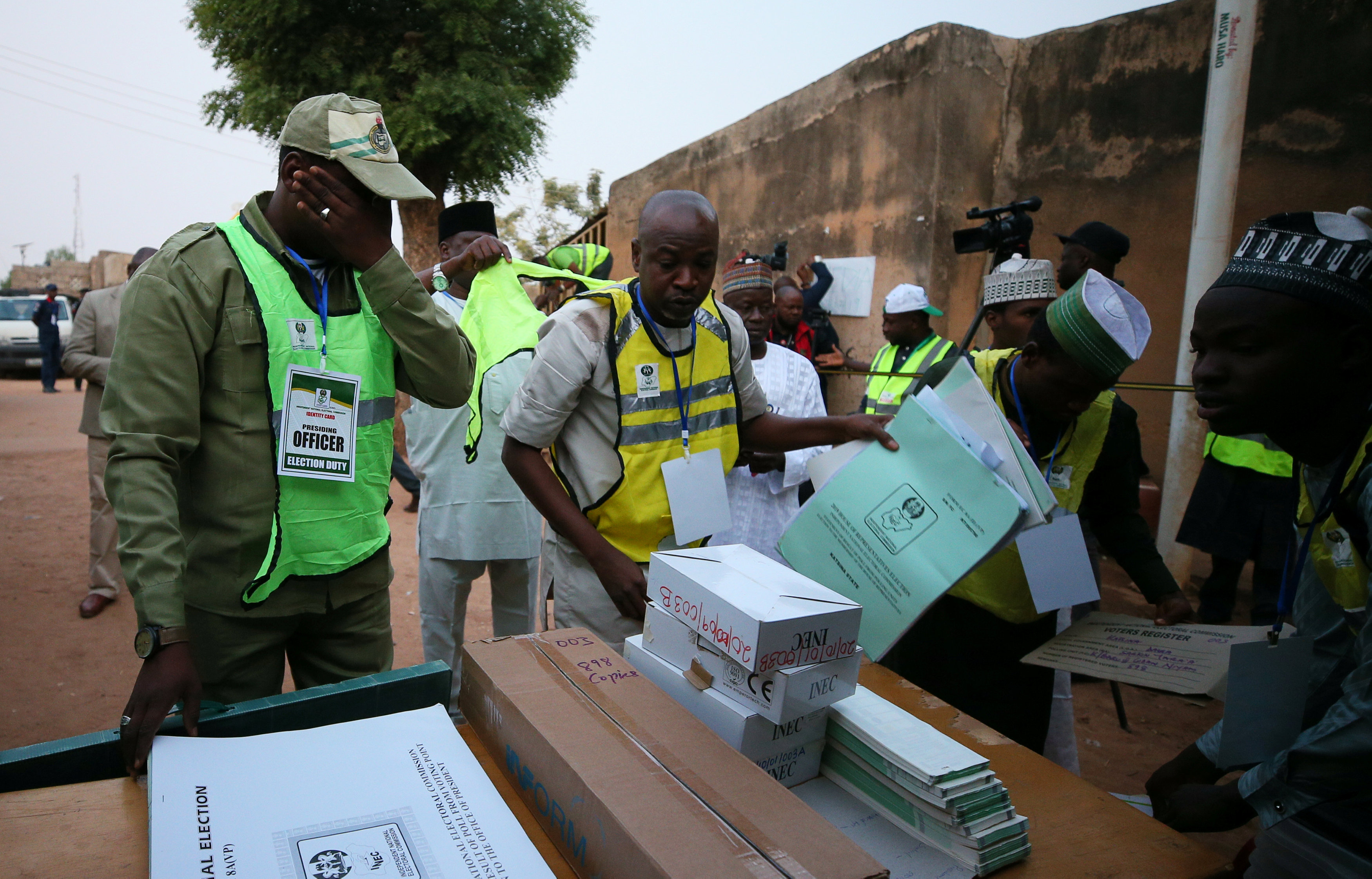 Des agents de la commission électorale nigériane préparent des cartons et documents de vote devant un bureau de vote