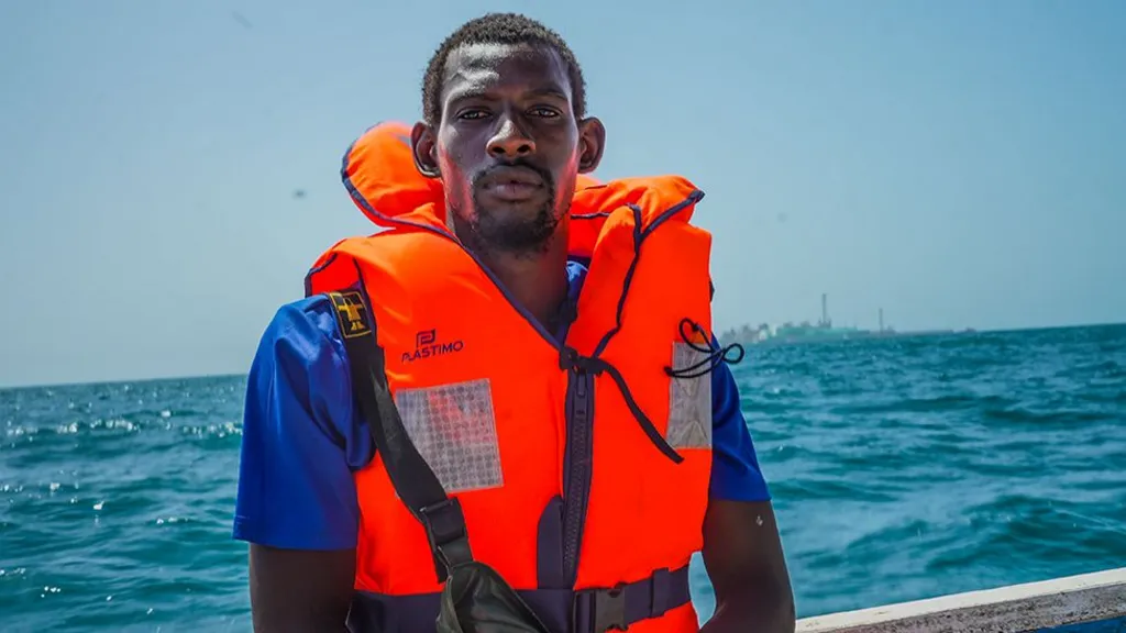 Un pêcheur portant un gilet de sauvetage orange à bord d'une embarcation en mer, photo d'archives