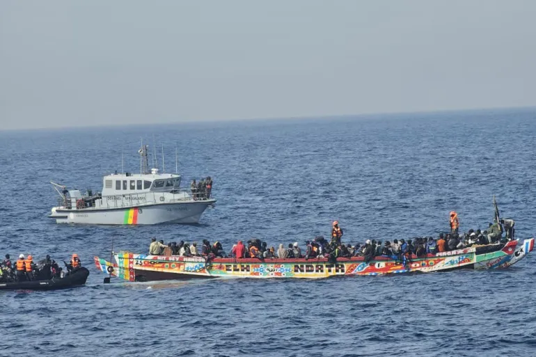 Une pirogue colorée surchargée de migrants escortée par un patrouilleur en mer