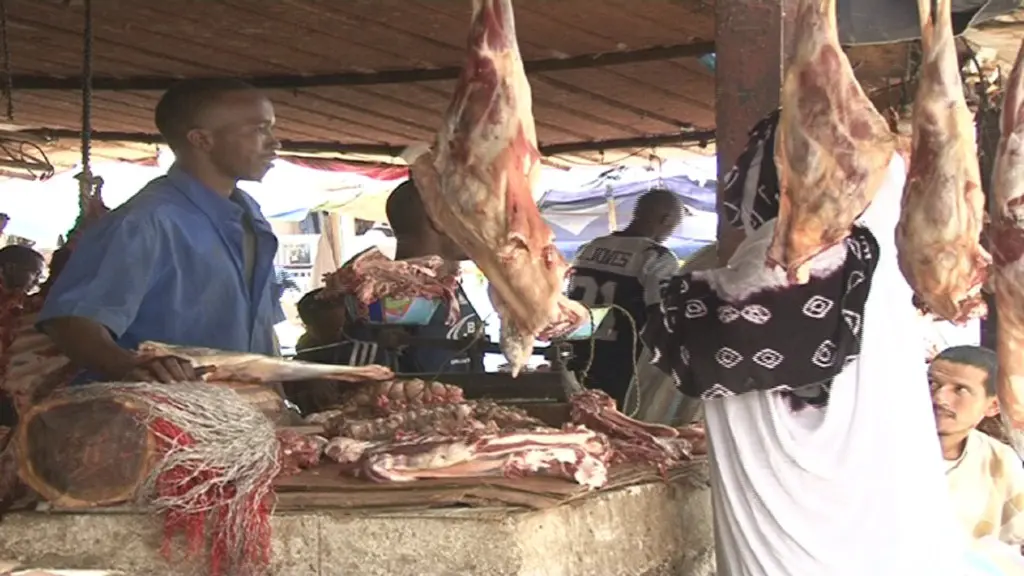 Des carcasses suspendues dans un étal de boucherie d'un marché populaire, un vendeur derrière le comptoir, photo d'archives