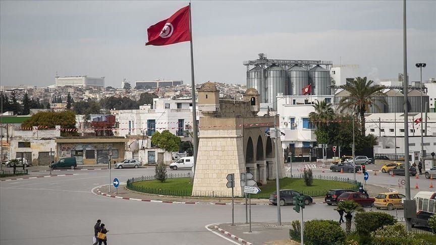 Un rond-point à Tunis avec un drapeau tunisien et des silos en arrière-plan