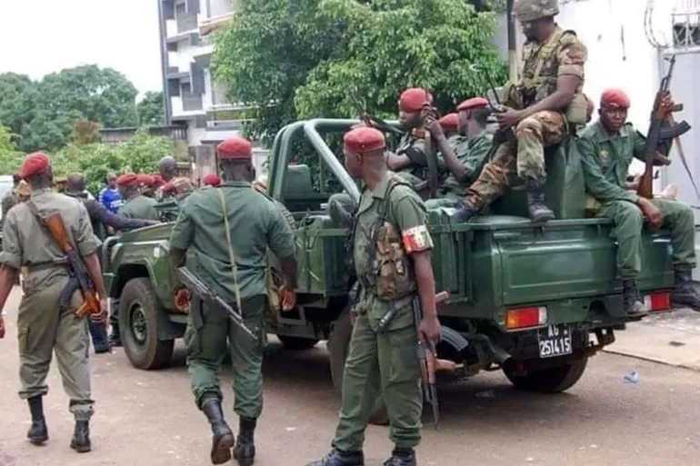Militaires guinéens en béret rouge, armés, autour d'un véhicule militaire vert dans une rue, photo d'archives