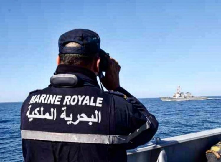 Un marin portant un gilet « Marine royale » observe la mer aux jumelles, un navire à l'horizon, photo d'archives