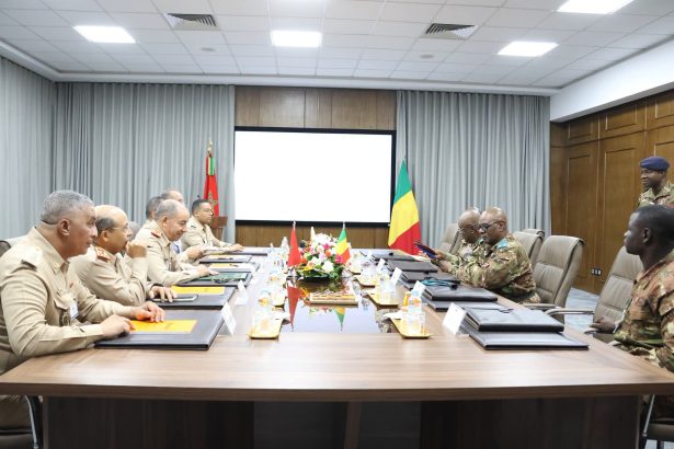 Des officiers marocains et maliens autour d'une table de réunion, devant les drapeaux des deux pays