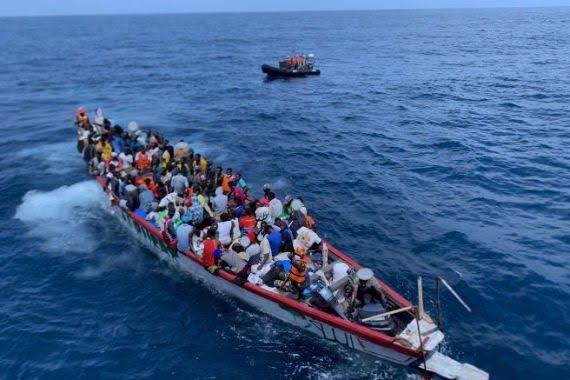 Une pirogue chargée de migrants en mer, près d'un bateau de secours